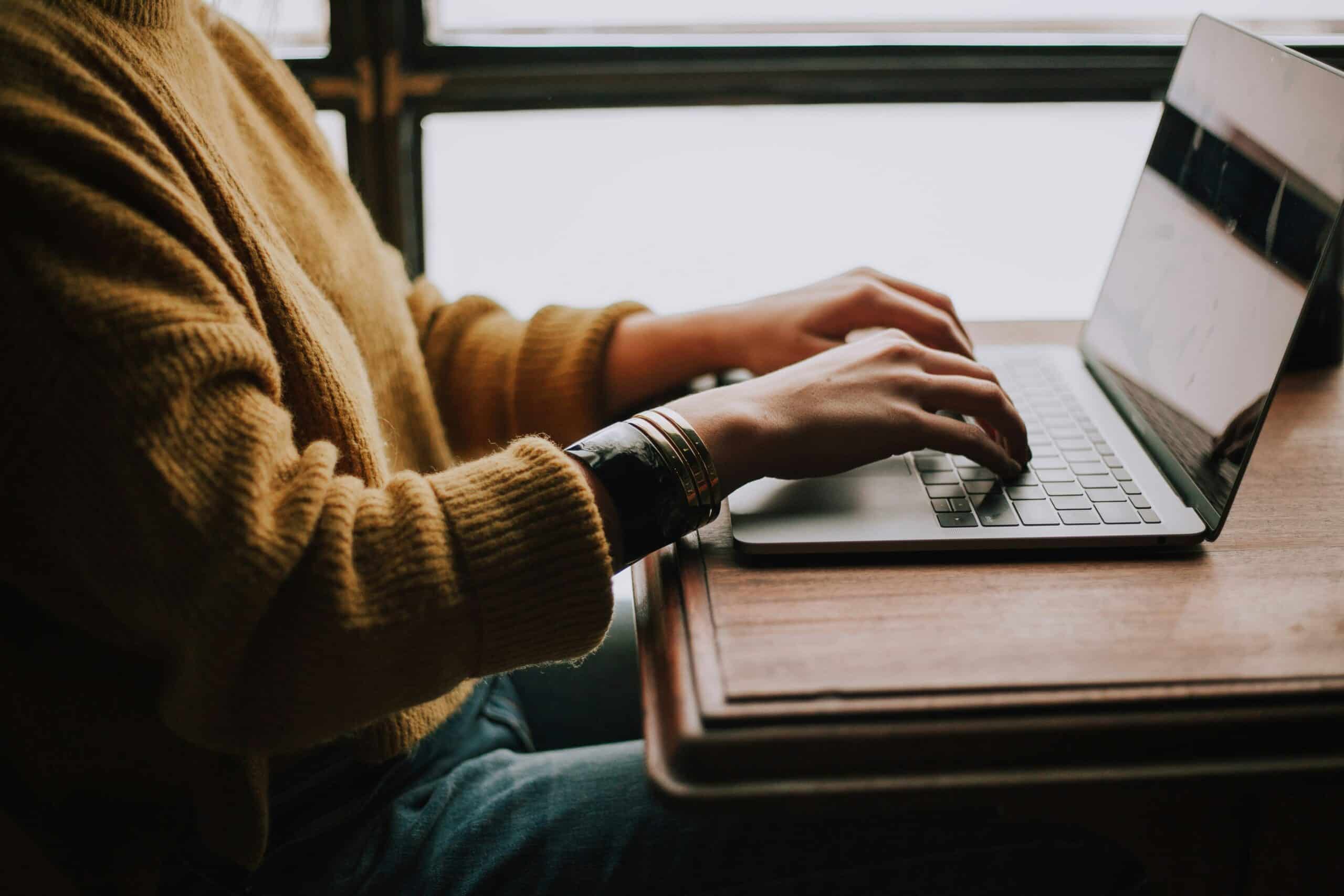christin-hume-mfB1B1s4sMc-unsplash-scaled.jpg person sitting front of laptop